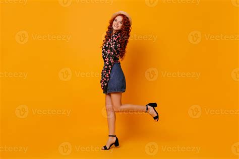 attractive long haired redhead lady in miniskirt made of denim beautiful blouse and boater is