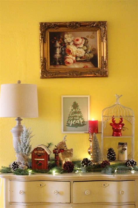 A White Dresser Topped With Christmas Decorations Next To A Painting