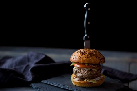 Burger Skewered With Knife Near Black Textile Photo Free Food Image