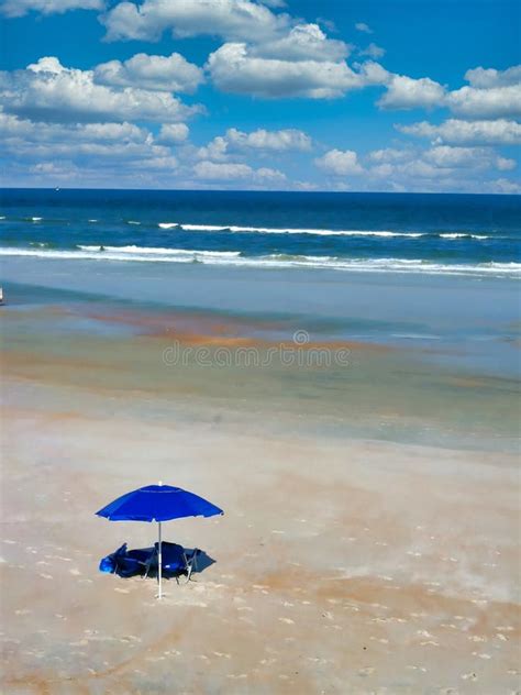 A Peaceful And Serene Beach Scene With Sand Waves Clouds And Umbrella