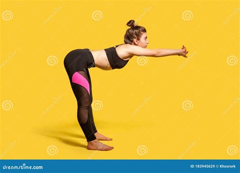 side view athletic woman with hair bun in tight sportswear doing sport bending and stretching