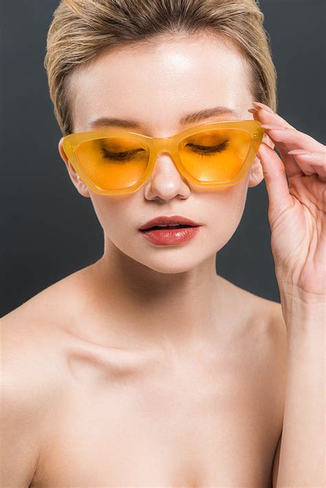유토이미지 Beautiful Young Woman Touching Yellow Sunglasses Isolated On Black
