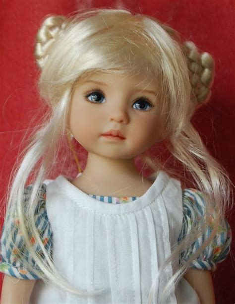 A Doll With Blonde Hair And Blue Eyes Wearing A White Dress On A Red