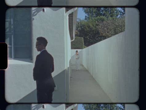 Two Shots Of A Man In A Suit And Tie Walking Down A Sidewalk Next To A Building