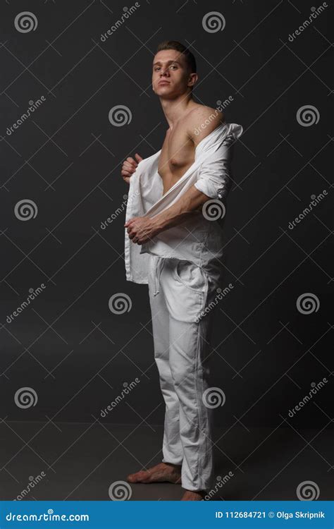 Un Individuo Con Un Torso Desnudo En Los Pantalones Blancos Y En Una Camisa Blanca Se Coloca