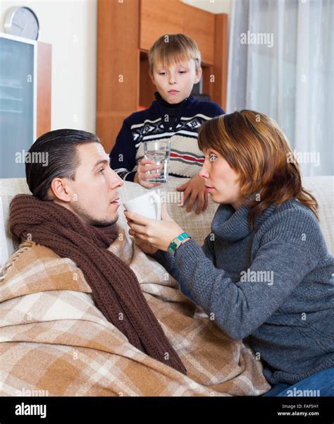 Sick Man Surrounded By Caring Wife And Loving Teen Son At Home Stock