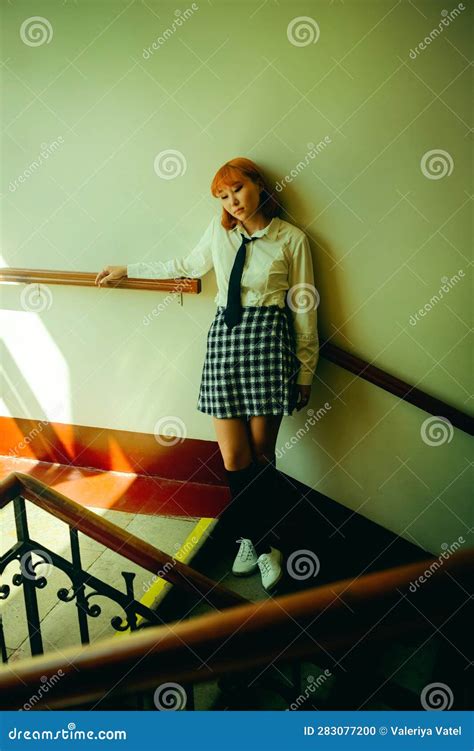 A Ginger Asian Schoolgirl Stands On The School Staircase On A Sunny Day