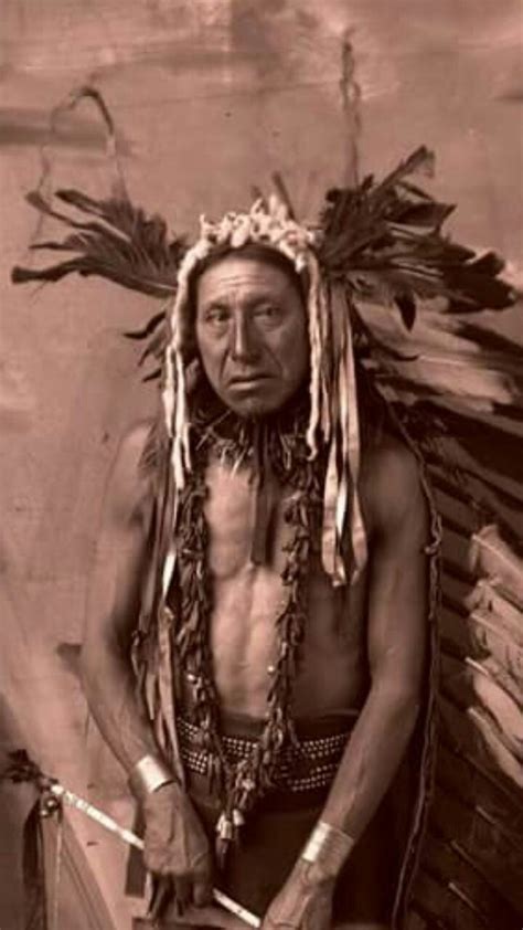 An Old Photo Of A Native American Man Holding A Knife And Looking At The Camera