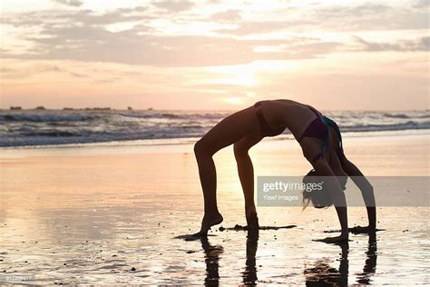 Mid Adult Woman Bending Over Backwards On Beach At Sunset Nosara