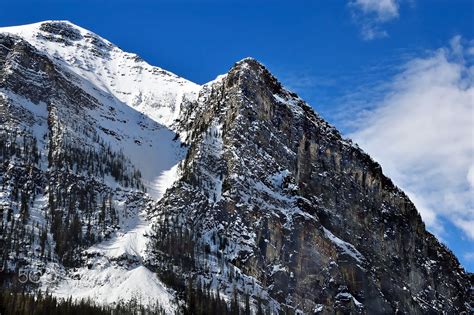 Sun Snow Summit Close Up Shot Of Steep Cliff Mountain Side With Snowy