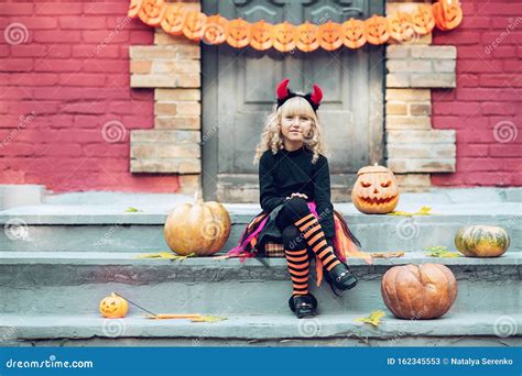 Little Girl In Witch Costume Celebrate Halloween Outdoor And Have Fun