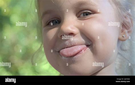 Portrait Of Cute Little Girl Sticking Her Tongue Out And Smiling After