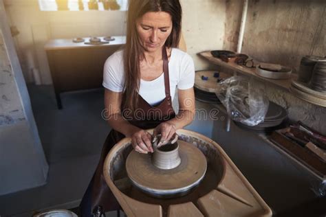 Artisan Working Clay On A Pottery Wheel In Her Studio Stock Image