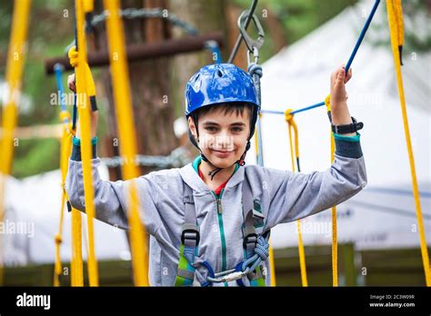 Young Boy Climbing Pass Obstacles In Rope Child In Forest Adventure