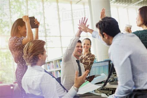 Business People High Fiving And Celebrating In Office Stock Photo