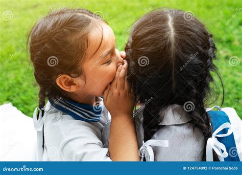 Two Young Girls Whispering And Sharing A Secret During Playground
