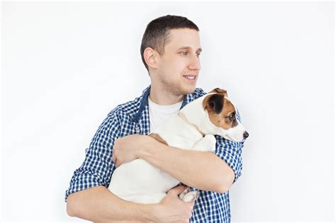 Premium Photo A Smiling Handsome Man Holding A Purebred Dog On A