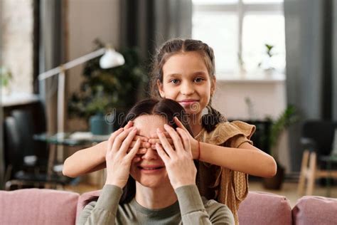 Happy Cute Little Girl Covering Eyes Of Her Mom By Hands Stock Photo