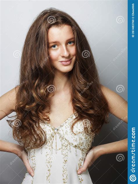 Beautiful Young Woman Model With Long Curly Hair In A White Dress Posing With Her Hands On Her