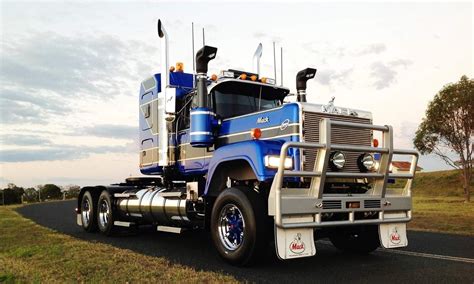 A Blue And Silver Semi Truck Driving Down The Road With Trees In The