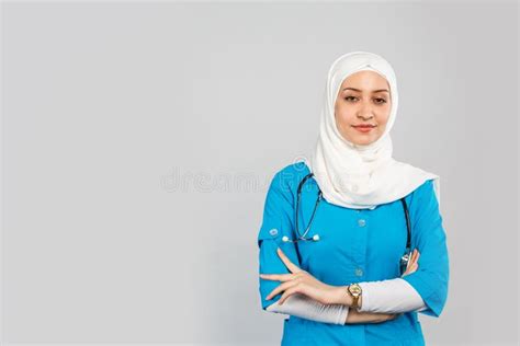 beautiful modern muslim doctor or nurse in hijab on a gray background blue uniform stock image