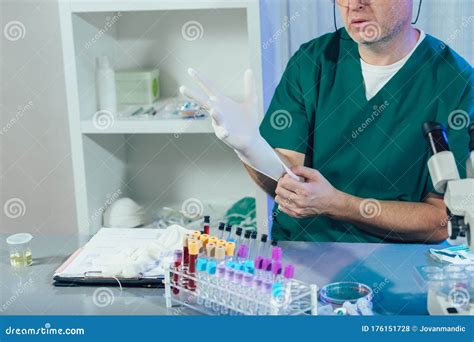 Laboratory Assistant In White Uniform Sitting In Lab And Putting