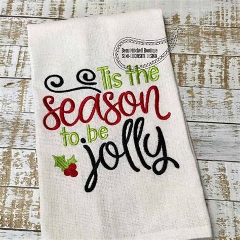 A White Dish Towel With The Words Tis The Season To Be Jolly