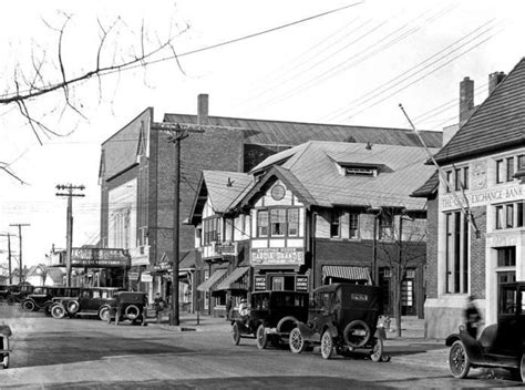 An Old Black And White Photo Of Cars Parked In Front Of Buildings