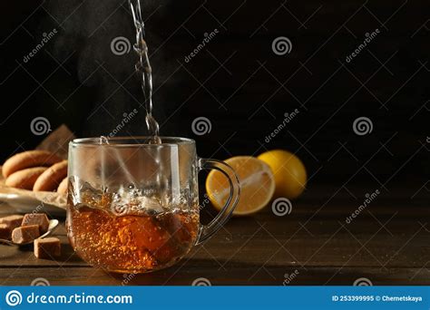 Pouring Hot Water Into Glass Cup With Tea Bag At Dark Wooden Table Space For Text Stock Image