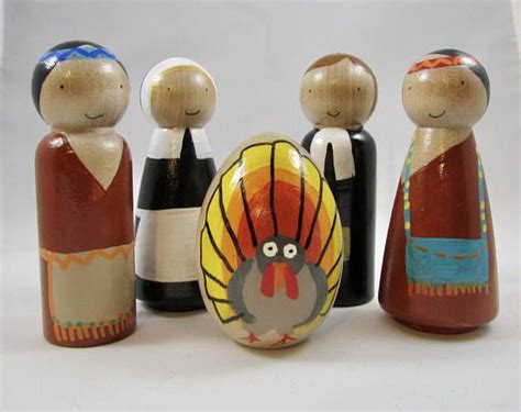 A Group Of Wooden Dolls Standing Next To Each Other On A White Surface With A Turkey In The Middle