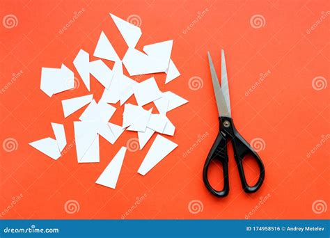Finely Cut Pieces Of Paper On A Red Background And Scissors With Black
