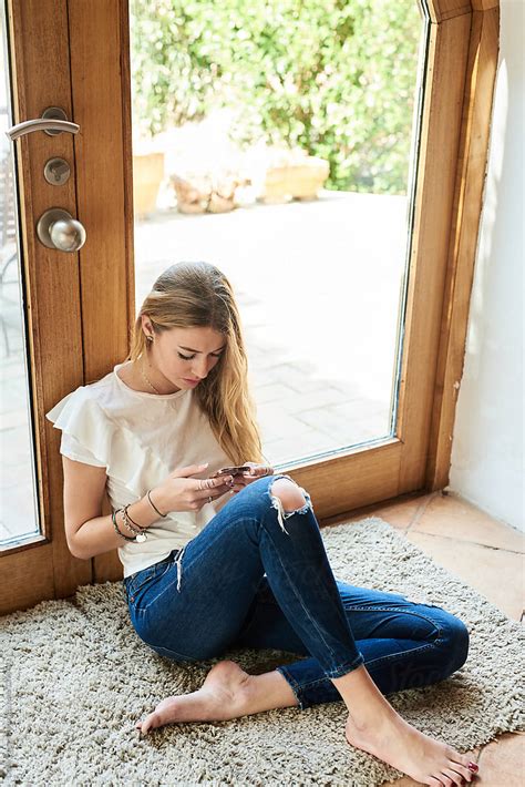 Barefoot Woman Browsing Cell Phone On Rug By Stocksy Contributor