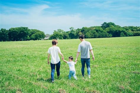 Los Padres Y Su Hijo Tomados De La Mano Y Caminando En Un Espacio Verde