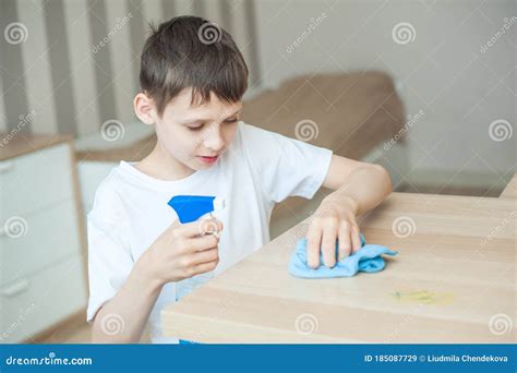 A School Aged Boy Cleans The Room Puts Detergent On The Table In His