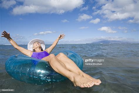 Mature Woman Floating On Inner Tube In Sea Arms Outstretched Photo