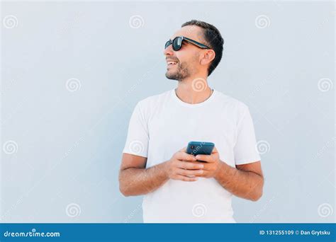 Handsome Young Man In Sunglasses Smile And Use Phone Isolated On Blue