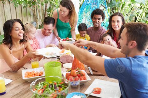 Grupo De Familias Disfrutando De Comida Al Aire Libre En Casa 937805