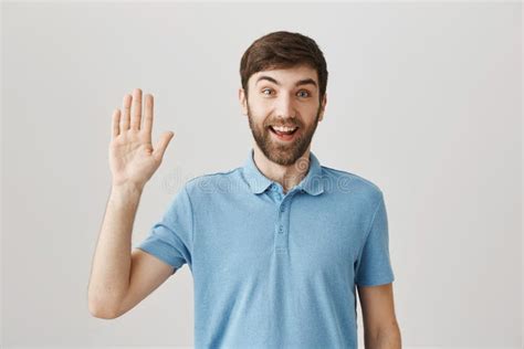 Positive Bearded Guy Smiling Friendly And Waving As If Greeting Someone