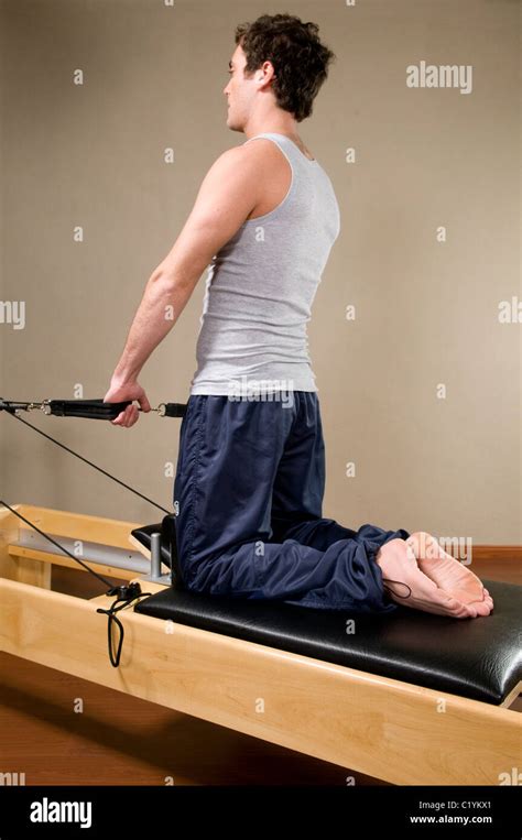 Man Wearing A Gray Top And Blue Trousers Knelt Down On An Exercise