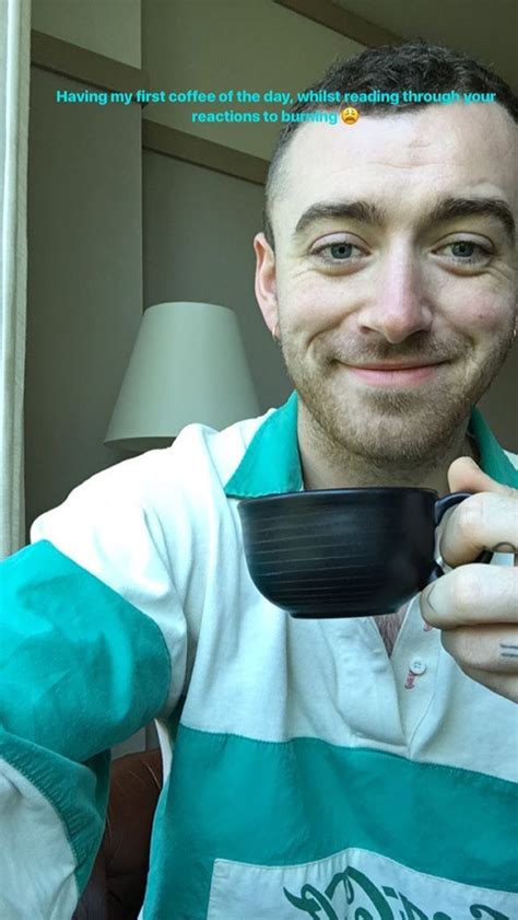 A Man Holding A Black Cup In His Right Hand And Looking At The Camera With An Intense Smile On