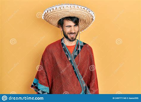 Young Hispanic Man Holding Mexican Hat Winking Looking At The Camera