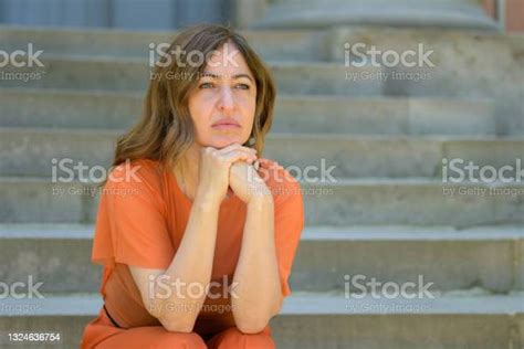 Bored Woman Sitting Waiting On Steps With Thoughtful Expression Stock