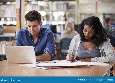 Two Mature Students Working On Laptop In College Library Stock Image
