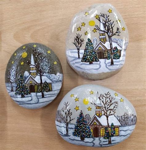 Three Painted Rocks Sitting On Top Of A Wooden Table Covered In Snow