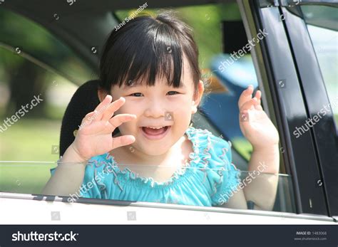 Girl Smiling And Waving Goodbye In A Car Stock Photo