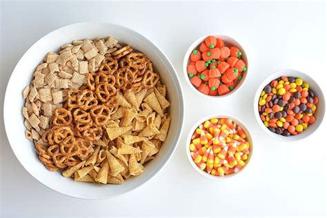 Three Bowls Filled With Cereal Candy Corn And Pretzels Next To Each Other