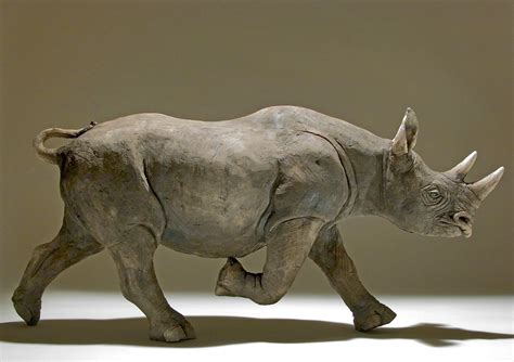 A Statue Of A Rhino Running On A White Surface