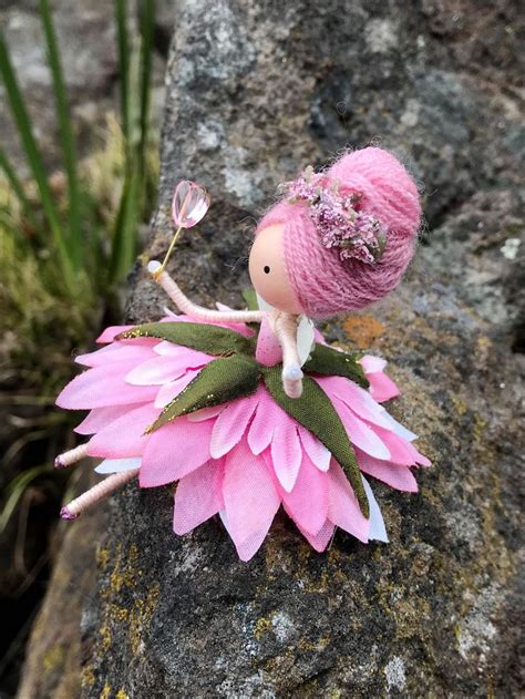A Pink Flower Fairy Sitting On Top Of A Rock