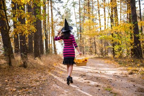 Premium Photo Young Witch Walking In Autumn Forests With A Basket
