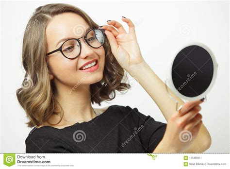 Joyful Woman Trying On Glasses At The Mirror And Smiling Happily Has A